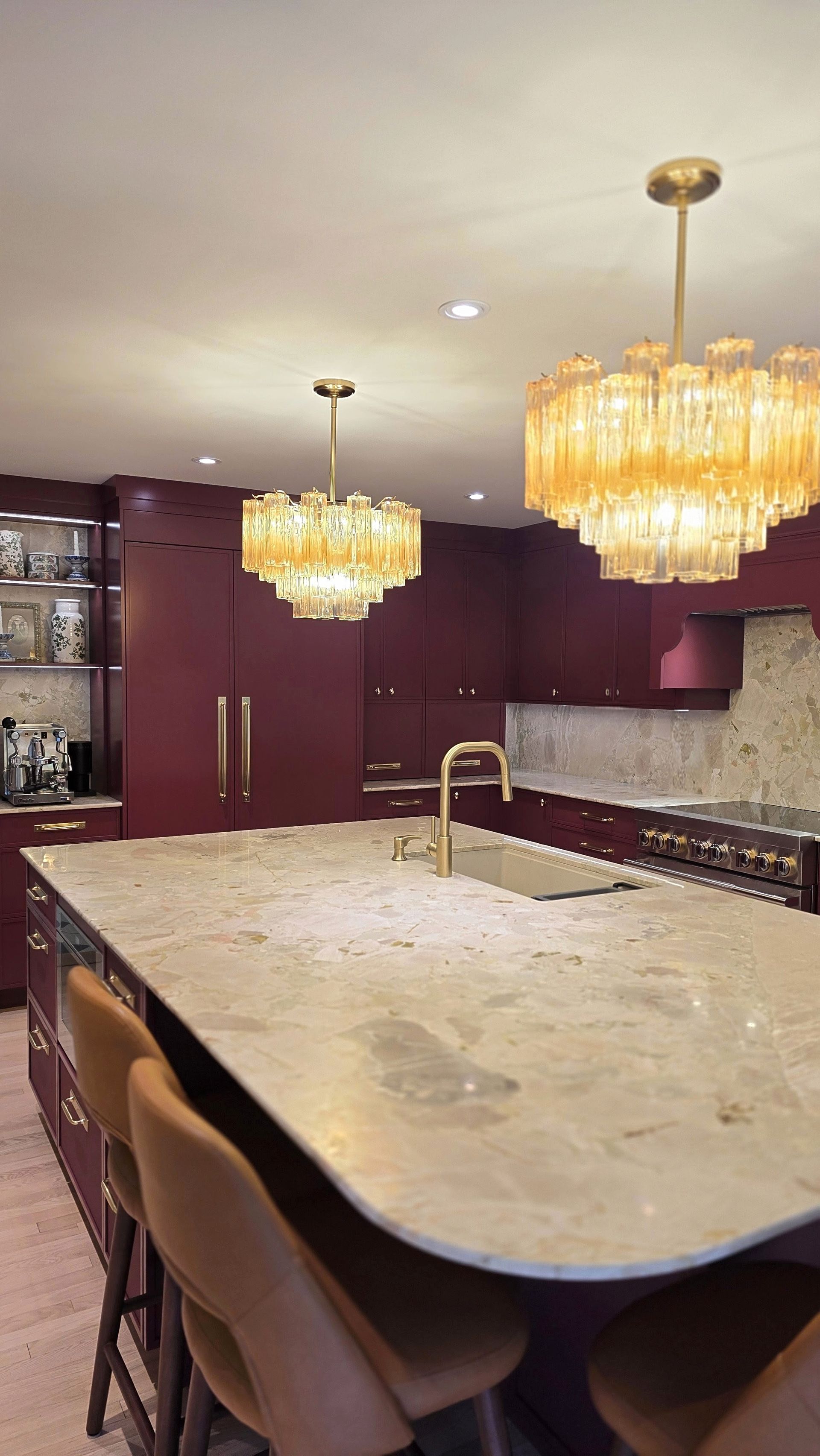 Red kitchen cupboards against pale stone counters — kitchen renovation by Corey Bowen Construction